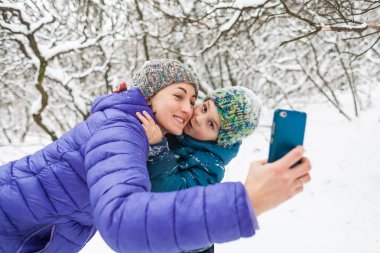 Bir kadın oğlu ile bir kış yürüyüşü bir selfie alır.