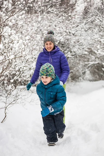 El niño huye de su madre en un camino nevado . — Foto de Stock