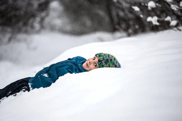 Το αγόρι κείτεται στο χιόνι. — Φωτογραφία Αρχείου