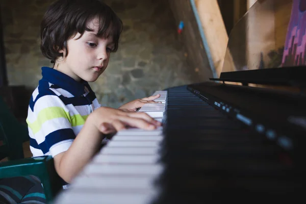 Un niño aprende a tocar el piano . — Foto de Stock