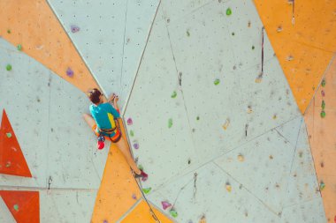 Bir kız bir tırmanma duvarı tırmanıyor.