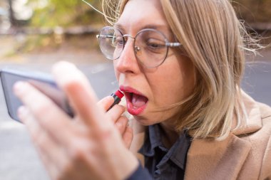 Kadın dudaklarını kırmızı rujla boyuyor..