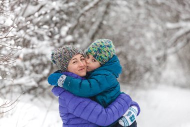Örgü şapkalı bir çocuk annesini öper..