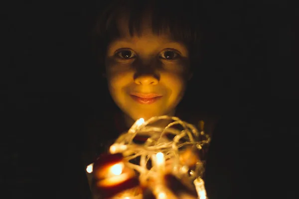 El chico sostiene una guirnalda de Navidad en sus manos. . —  Fotos de Stock