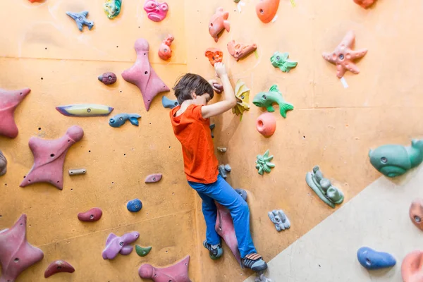 Niño escalando en la pared de rocas artificiales en el gimnasio — Foto de Stock