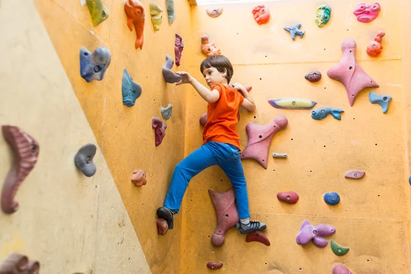 Niño escalando en la pared de rocas artificiales en el gimnasio — Foto de Stock