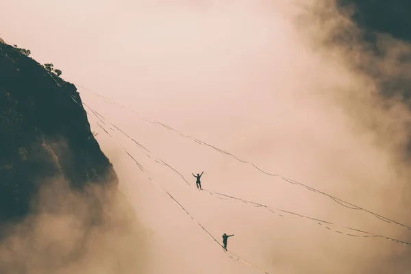 云彩上方的一条线上有两个登山者. — 图库照片