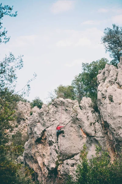 En flicka klättrar en rock. — Stockfoto