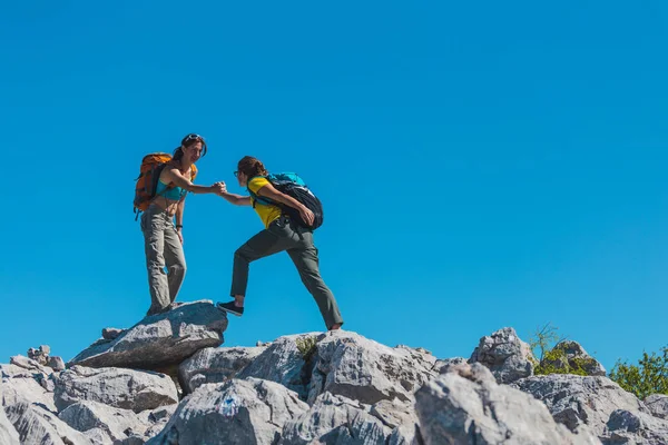 Bir kadın arkadaşının taşa tırmanmasına yardım eder.. — Stok fotoğraf