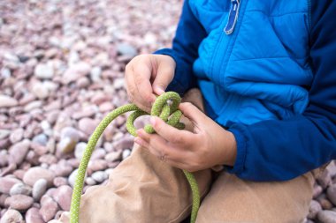 Bir çocuk ipten düğüm örmeyi öğrenir..
