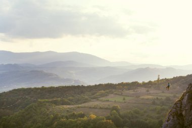 Bir adam uzatılmış bir askıda oturur..