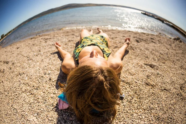 Una mujer está tomando el sol en una playa . —  Fotos de Stock