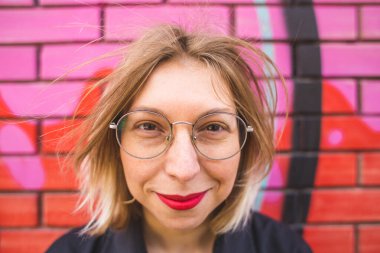 Duvarda gözlüklü bir sarışının portresi.