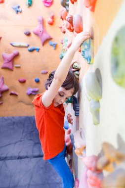 Beden dersinde çocuk yapay kaya duvarına tırmanıyor.