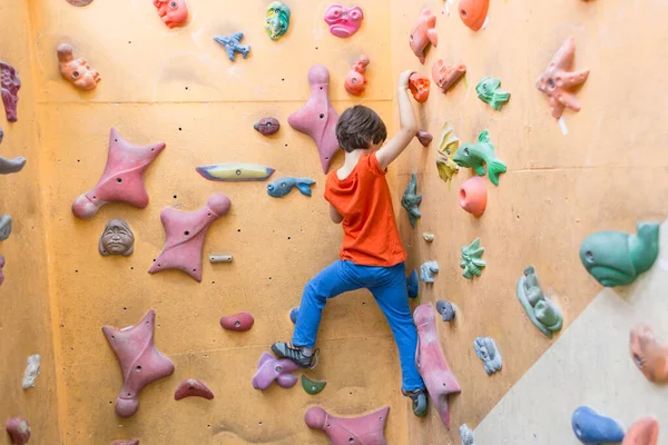 Niño escalando en la pared de rocas artificiales en el gimnasio — Foto de Stock