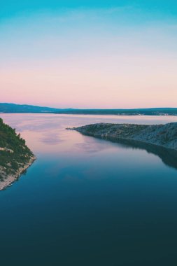 Deniz ve gökyüzü bulutlu gün batımında.
