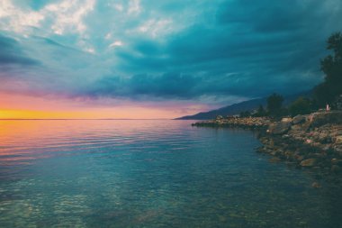 Deniz ve gökyüzü bulutlu gün batımında.