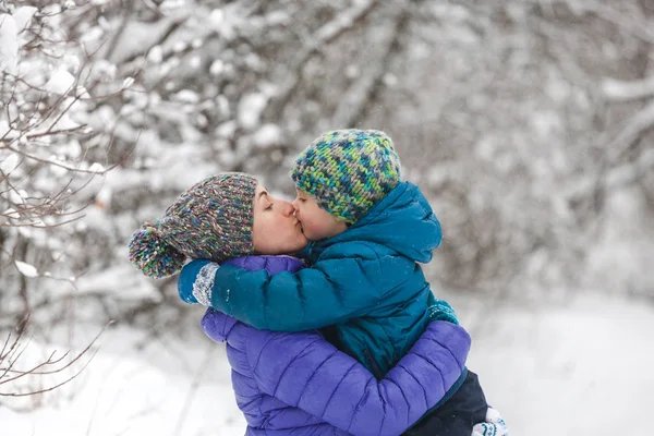 Un niño en un sombrero de punto besa a su madre . — Foto de Stock