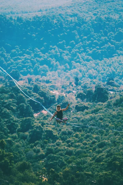 A woman sits on a stretched sling. — ストック写真