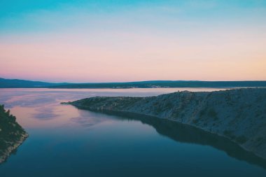Deniz ve gökyüzü bulutlu gün batımında.