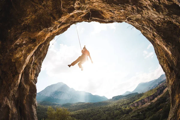 岩の登山ロープにかかっている 女性がアーチの形をした岩に登る 少女は洞窟に登る 裏切るためのロープを登る トルコのロッククライミング — ストック写真