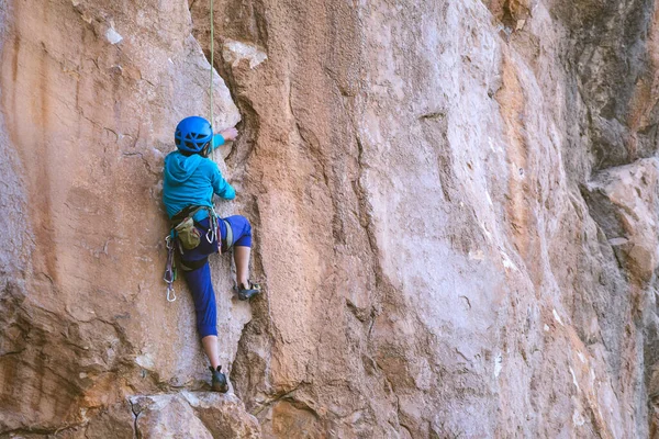 ヘルメットの女性は美しいオレンジの岩を登る クライミング保護装置 登山の安全性 ロッククライマーは 自然の地形上で困難なルートを克服します トルコのロッククライミング — ストック写真