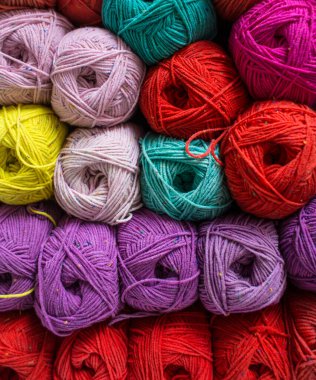 Renkli ipliğin arka planı. Toplar yakın plan çekimde. Dikiş işi için malzemeler. Dükkanda iplikle doldur. Örgü örmek için çok renkli iplikleri olan raflar.