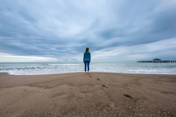 Una Chica Está Parada Una Playa Arena Una Mujer Está — Foto de Stock