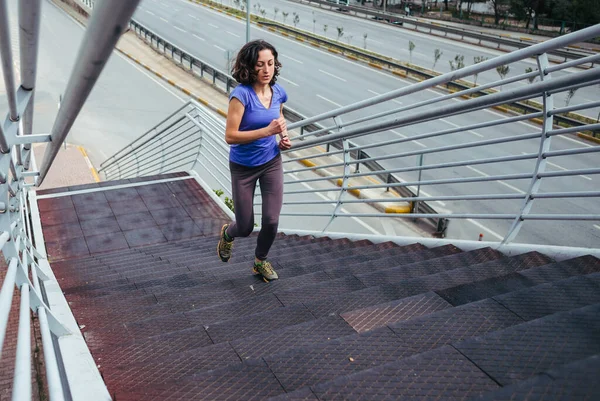 一个女人跑上楼梯 在城市里进行训练慢跑 实现这个目标 胜利的渴望 女孩训练耐力 — 图库照片