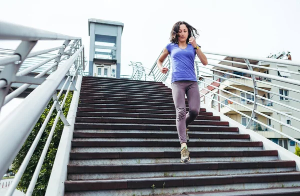 A woman runs up the stairs. Running training in the city. Jogging. Reaching the goal. The desire for victory. Workout.