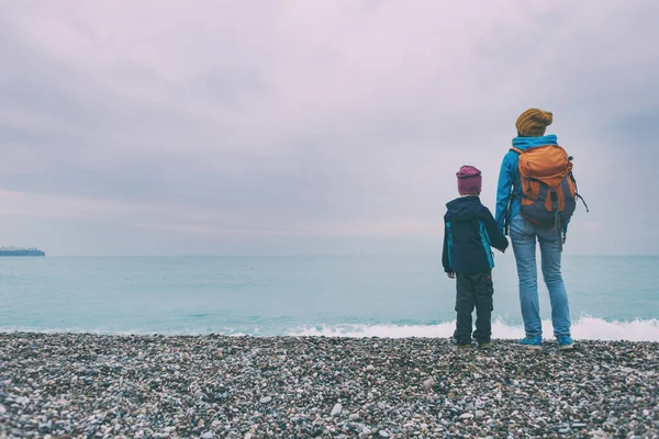 秋天的一个雨天 一个女人和一个小孩沿着海滨散步 和妈妈在一起的男孩走进了大海 带着云彩的海洋和天空 — 图库照片