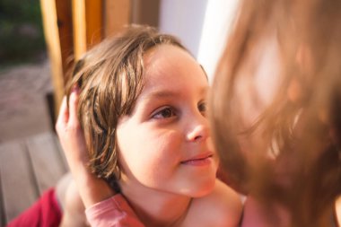 Annesine sarılan bir çocuğun portresi, annesiyle vakit geçiren bir çocuk, oğluna nazikçe sarılan bir kadın. Tatlı çocuk sevgili annesine bakıyor. Gün batımı ışığı saçların arasından geçiyor.