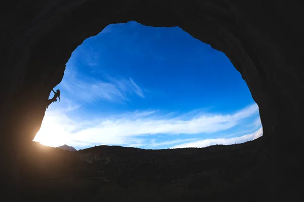 岩登りのシルエットアーチ型の岩を登る女性は 日没の空に対して洞窟の中で困難な登山ルートを克服し トルコでロッククライミング — ストック写真