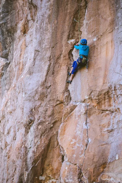 ヘルメットの女性は美しいオレンジの岩を登る クライミング保護装置 登山の安全性 ロッククライマーは 自然の地形上で困難なルートを克服します トルコのロッククライミング — ストック写真