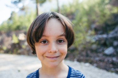 Tatlı bir çocuğun portresi, ormanda yürüyüş yapan bir çocuk kahverengi gözlü bir çocuk, kamerada poz veren bir çocuk..