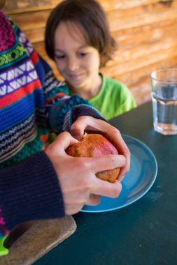 Mavi bir tabakta olgun, sulu bir nar. Çocuk, annesinin narı kesişini izliyor. Sağlıklı meyve ikiye bölünür..
