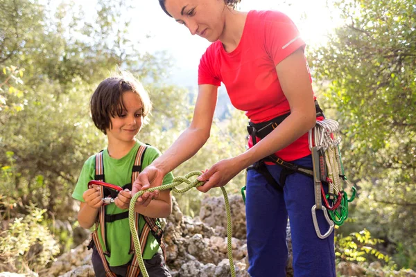 The mother teaches the child to tie a safety knot for climbing, Protective equipment for climbing and sports tourism, A boy learns to knit the safety knot from the rope, Climbing rope for belaying.