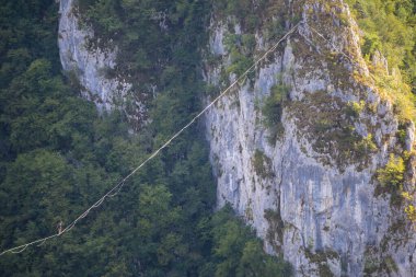 Dağlarda yüksek bir yer. Bir adam askı takıyor. Highline çizgide. Bir ip cambazı dengeyi yakalar. Eşitlik. Gergin bir durumda güven.