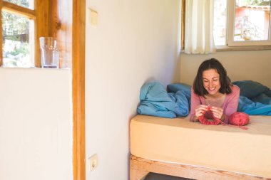 Kadın yatakta örgü örüyor, kadın elleri şapka örüyor, karantina sırasında yaratıcılıkla meşgul, el yapımı, favori ev hobisi....