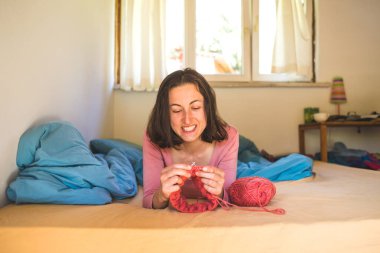 Kadın yatakta örgü örüyor, kadın elleri şapka örüyor, karantina sırasında yaratıcılıkla meşgul, el yapımı, favori ev hobisi....