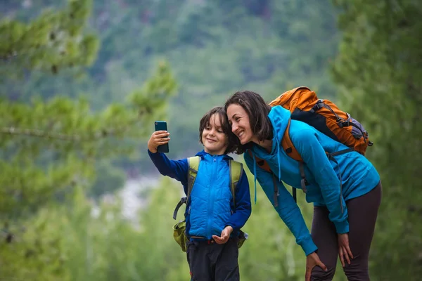 Barn Med Ryggsekk Tar Selfie Smarttelefon Med Mamma Bakgrunnen Fjellskog – stockfoto