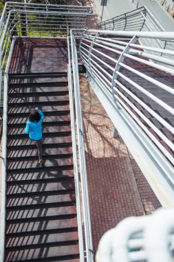 Bir kadın merdivenlerden yukarı koşuyor. Şehirde koşu eğitimi. Koşuyordum. Hedefe ulaşmak. Zafer arzusu. Antrenman yapıyorum. Kız dayanıklılık eğitimi alıyor.