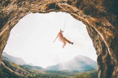Kaya tırmanışçısı ipte sallanıyor. Bir kadın kemer şeklinde bir kayaya tırmanıyor. Kız mağaraya tırmanıyor. İpi bağlamak için tırmanma ipi. Türkiye 'de kaya tırmanışı .