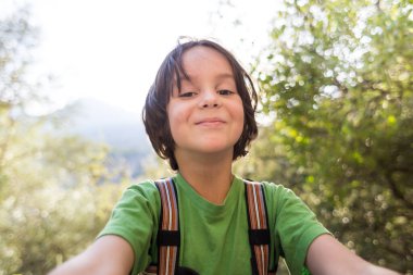 Bir çocuk ormanın arka planında selfie çeker, çocuk akıllı bir telefonla fotoğraflanır, gülümseyen bir çocuk parkta yürür..