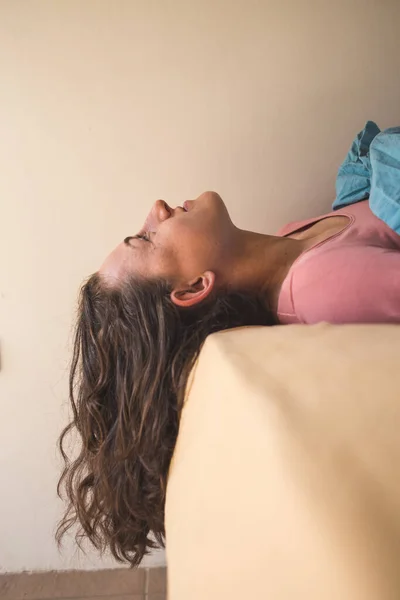 ベッドの上に女性が寝そべっていて 髪が垂れている 巻き毛のブルネットの肖像 — ストック写真