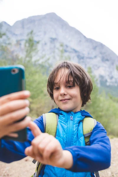 Menino Com Uma Mochila Faz Selfie Smartphone Fundo Belas Montanhas — Fotografia de Stock
