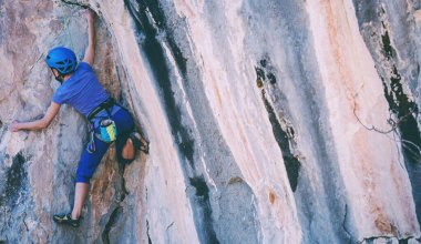 Kasklı bir kadın güzel mavi bir kayaya tırmanır. Koruyucu ekipmana tırmanıyorum. Tırmanırken güvenlik. Kaya tırmanışçısı doğal bir arazide zorlu bir rotanın üstesinden gelir. Türkiye 'de kaya tırmanışı.