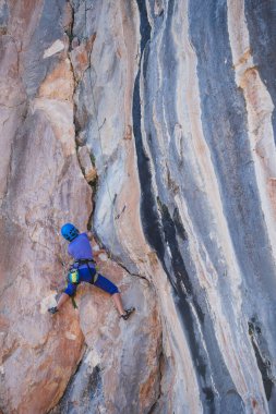 Kasklı bir kadın güzel mavi bir kayaya tırmanır. Koruyucu ekipmana tırmanıyorum. Tırmanırken güvenlik. Kaya tırmanışçısı doğal bir arazide zorlu bir rotanın üstesinden gelir. Türkiye 'de kaya tırmanışı.
