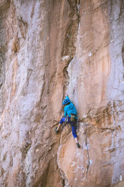 ヘルメットの女性は美しいオレンジの岩を登る クライミング保護装置 登山の安全性 ロッククライマーは 自然の地形上で困難なルートを克服します トルコのロッククライミング — ストック写真