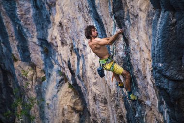 Güçlü bir adam kayaya tırmanır, güçlü sırt kasları, Türkiye 'de kaya tırmanışı, dayanıklılık ve güç eğitimi alır, ekstrem sporlarda çalışan bir adam, dağcı doğada eğitim görür..